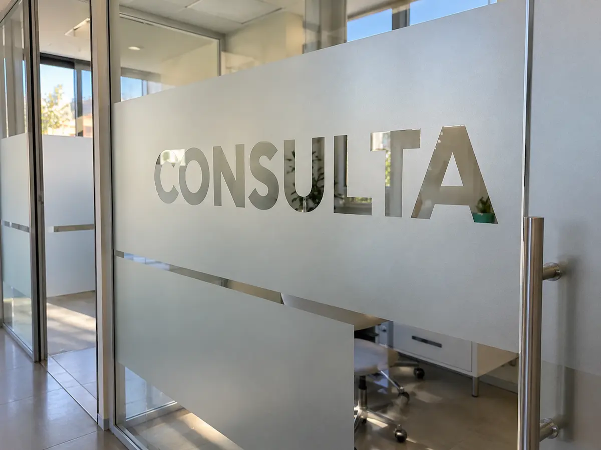 Mampara de cristal de una clínica con vinilo al ácido de efecto esmerilado y la palabra CONSULTA recortada en transparente